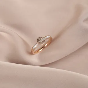 Close-up of a rose gold ring featuring a white shell inlay and engraved circular link