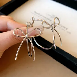Close-up of elegant silver bow knot hoop earrings showing delicate metal wire detail