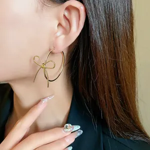 Elegant gold bowknot hoop earrings shown as a detailed close-up on an Asian model.