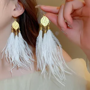 Detailed view of bohemian style gold-tone dangle earrings with fluffy white feather tassels