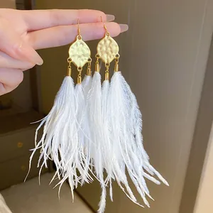 Close-up of bohemian gold hammered metal earrings with long white feather tassels