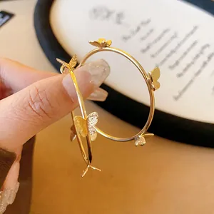 Vue détaillée de boucles d'oreilles créoles papillon dorées avec des tiges en argent s925