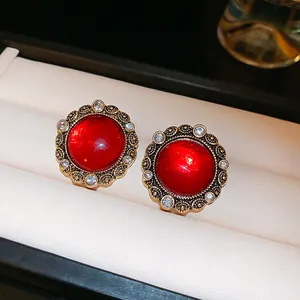 Detailed view of elegant red crystal stud earrings with golden filigree and silver pin