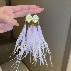Close-up detail of bohemian style pale lavender feather tassel earrings with textured gold