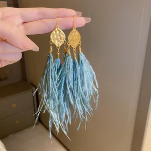 Detail of Bohemian vintage earrings with blue feather tassels and hammered gold metal
