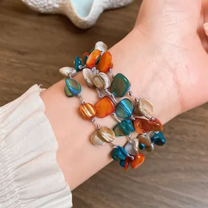 Detail showing colorful irregular shell pieces on a bohemian multilayer bracelet