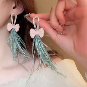Detailed close-up of bohemian earrings featuring pink bows and green feather tassels