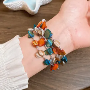 Close-up detail of a Bohemian multi-layer bracelet with colorful irregular shell beads