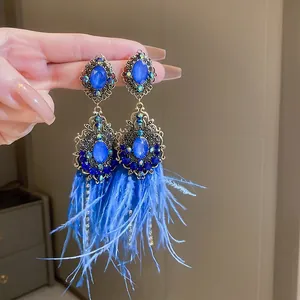Close-up detail of Bohemian vintage style blue feather tassel earrings with rhinestones.
