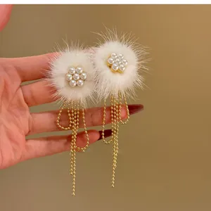 Detailansicht eleganter weißer Fellkugel-Ohrstecker mit Perlenblumen und Goldquasten