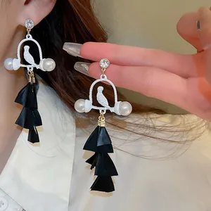 Detailed view of bohemian bird drop earrings with black feather tassels and pearls