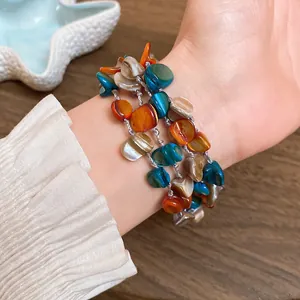 Close-up detail of bohemian multi-layer bracelet with irregular colorful shell beads