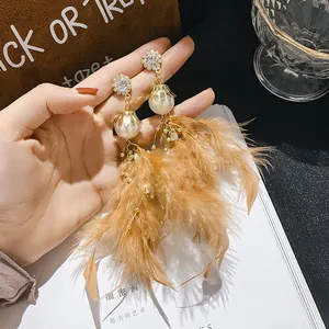 Detailed macro view of bohemian vintage feather tassel earrings with rhinestones and pearls