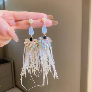 Detailed view of iridescent crystal and white feather tassel drop earrings