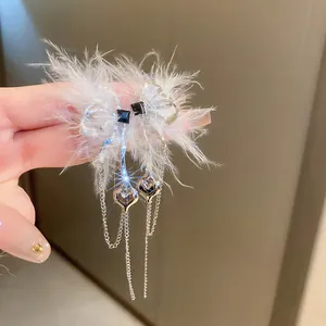 Close-up of Bohemian bow earrings with white feathers and silver chain tassels.