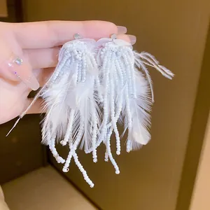 Detailed view of bohemian white feather tassel earrings with delicate beadwork strings