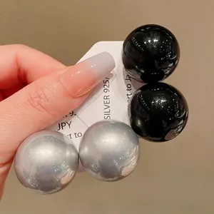 Stylish oversized glossy spherical stud earrings set in black and metallic silver finishes