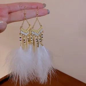 Detailed close-up showing bohemian white feather tassel earrings with elegant gold leaf accents