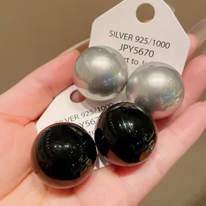 Detail of large glossy black and silver spherical stud earrings with 925 silver needles