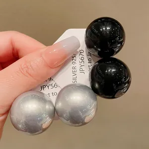 Detailed macro view of oversized black and silver spherical stud earrings on display card