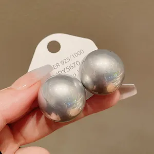 Close-up of oversized grey round pearl stud earrings with 925 silver needles for women