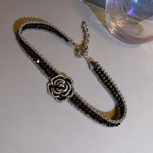 Dettaglio di un elegante choker camelia nero con strass scintillanti e perline di cristallo.