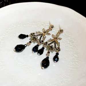 Détail de boucles d'oreilles vintage à pompons avec cristaux noirs et aiguilles argent