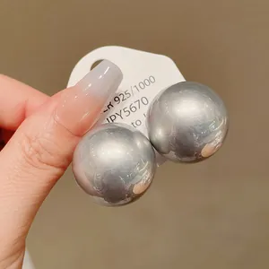Close-up of oversized silver spherical stud earrings on a white display card.