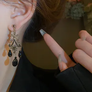 Gros plan de boucles d'oreilles pendantes vintage avec glands en cristal noir.