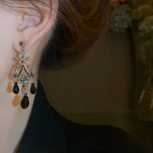Détail de boucles d'oreilles vintage avec pampilles en cristal noir portées à l'oreille