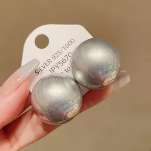 Oversized silver spherical stud earrings with high-polish mirror finish detail