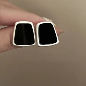 Close-up of minimalist black trapezoid resin stud earrings with silver-tone metal frame