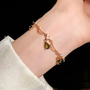 Elegantes goldenes Armband mit Schmetterling und grünen Zirkonanhängern am Handgelenk