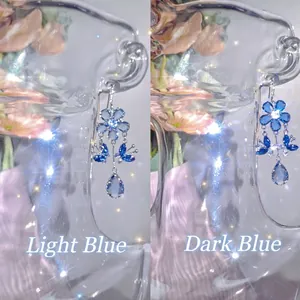Refined detail of zircon flower and butterfly tassel drop earrings in two blue shades.