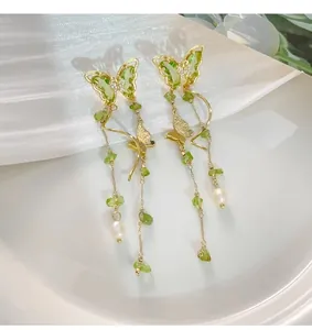 Close-up macro view of elegant green butterfly tassel earrings with pearls and stones