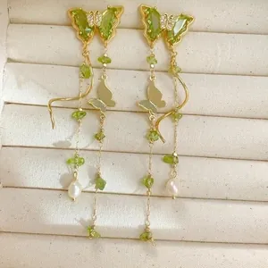 Élégantes boucles d'oreilles papillon dorées avec zircon vert et perles.