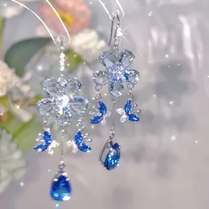 Close-up of blue cubic zirconia earrings with flower and butterfly tassel detail