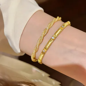 Close-up detail of Italian twisted mesh and stone-set golden bracelets on a wrist