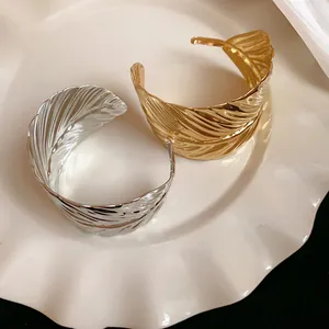 Detail showing intricate leaf pattern texture on gold and silver metallic cuff bracelets