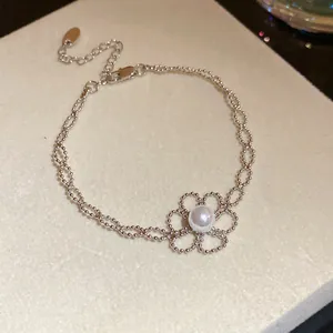 Detailansicht eines eleganten silbernen Perlenarmbands mit einem zarten Blumenanhänger aus Perlen