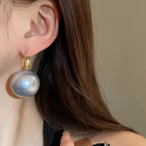 Close-up view of a French vintage large grey pearl earring worn by an Asian model