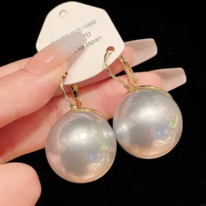 Close-up of elegant large round white pearl drop earrings with golden lever-back hooks