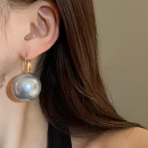 Detailed close-up view of French vintage large metallic grey pearl earrings worn on ear