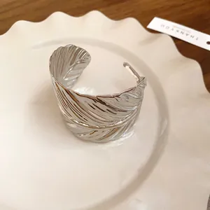 Detailed view of a silver-toned metal cuff bracelet with realistic leaf texture style.