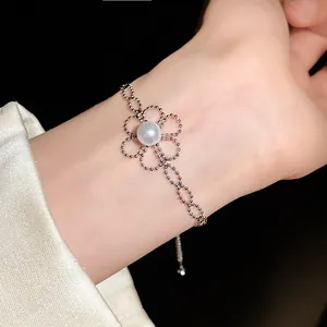Detaillierte Nahaufnahme eines zarten Perlenblumenarmbands am Handgelenk einer Frau