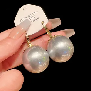 Macro view of large pearl drop earrings featuring elegant golden French style leverback clasps