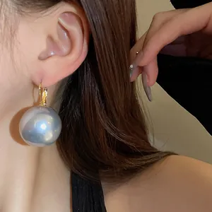 Close-up of a vintage French-style large metallic grey pearl earring worn on the ear.