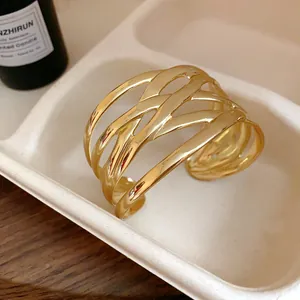 Detailed view of an elegant wide woven gold cuff bracelet with intricate metallic leaf texture.