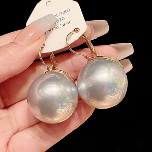 Detail view of large silver-grey pearl drop earrings with gold-toned lever-back clasps