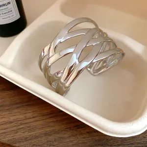 Close-up of polished silver wide cuff bracelet with a unique interwoven hollow-out design